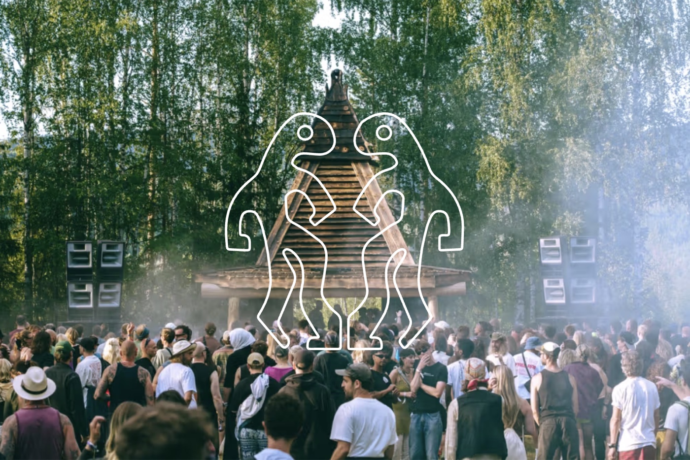 A crowd gathered before a pyramid-shaped stage at Monument Festival in a birch forest
